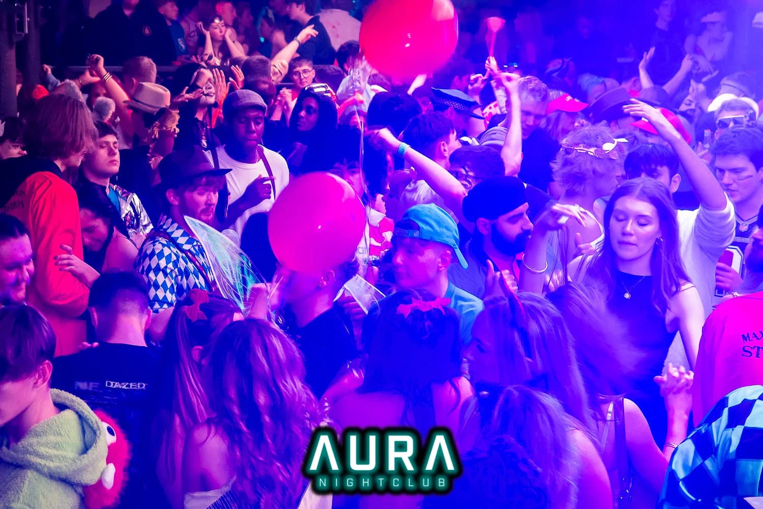 Energetic crowd celebrating with pink balloons